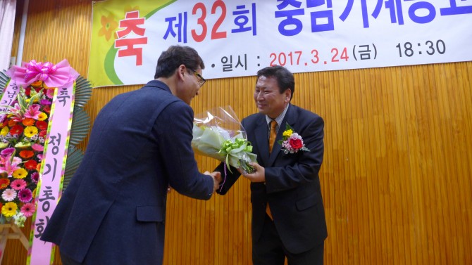 한흥교 사무총장이 한복수 동문에게 화환증정